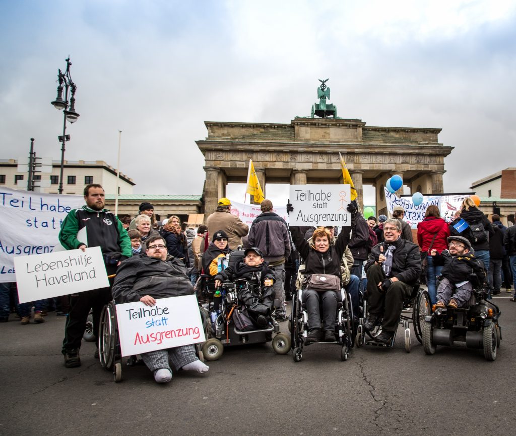 Ein Gruppenbild von Aktivist*innen mit Behinderung vor dem Brandenburger Tor.