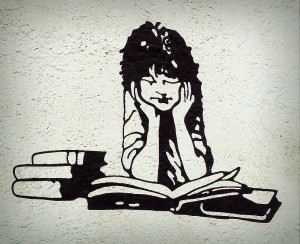 Eine Street-Art-Bild mit den Silhuetten eines Jungen, der Bücher liest.