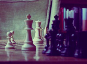 Foto: Mehrere schwarze und weisse Schachfiguren bei der die weisse Dame im Fokus steht.