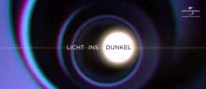 Screenshot der Sendung "Licht ins Dunkel" vom ORF. Zu sehen ist ein weiß-schwarzer Schriftzug vor blau-violett-schwarzen Ringen.