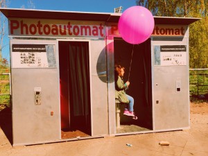 Ninia Binias sitzt in einem alten Photoautomaten und hält einen pinken Luftballon in der Hand