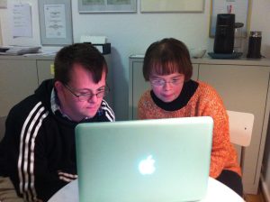 Ein Mann und eine Frau mit Down-Syndrom lesen am Laptop.