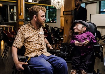 Luke Anderson und Raul Krauthausen unterhalten sich. Beide sitzen im Rollstuhl.
