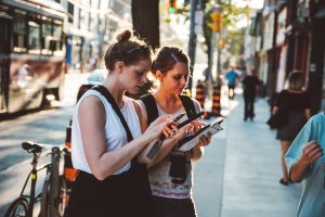 Zwei Frauen schauen während einer Mapping-Tour auf ihr Smartphone.