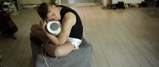 Ein junger Mann sitzt auf dem Fußboden und hält eine Lautsprecherbox in den Händen.