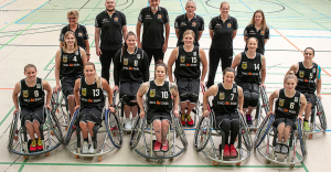 Das Team der deutschen Frauen im Rollstuhlbasketball stehen auf dem Spielfeld und gucken in die Kamera.