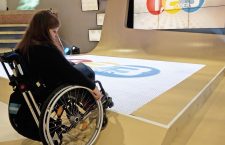 Judyta sitzt im Rollstuhl und versucht auf die Antwortfelder 1,2 oder 3 zu fahren.