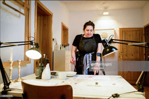 Annton Beate Schmidt steht in ihrem Atelier vor einem Tisch und malt.